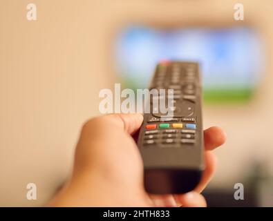 Bereit für einen Seifenopern-Marathon. POV-Aufnahme einer Person, die mit einer Fernbedienung auf einen Flachbildfernseher zielte. Stockfoto