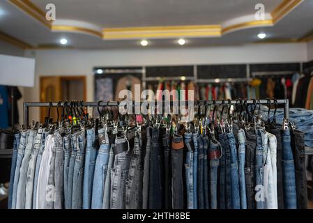 Shop von modischer europäischer Kleidung, Marken-Jeans in der Boutique an Kleiderbügeln, blaue Jeans. Kleidung Hintergrund Stockfoto