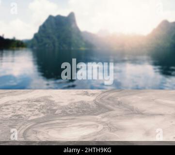 Leerraum von Marmortisch mit dem Hintergrund von See- und Bergkulisse am Morgen, aufgehende Sonne, leerer Raum für Produktpräsentation auf dem Tisch. Stockfoto