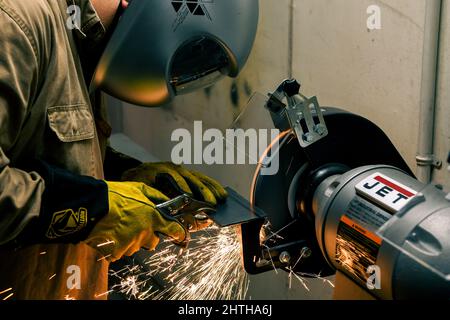 MISAWA, Japan (Feb 8, 2022) – Ian Acuzar, Chief Hull Technician, der der Naval Air Facility Misawa zugewiesen wurde, verwendet einen Bankschleifer in einem Hobbygeschäft im Militärflugplatz Misawa. Acuzar schleift das Metall, das er schneidet, so dass er glatt schweißen kann, wenn er den Leuten beibringt, wie man schweißen soll. (USA Navy Foto von Mass Communication Specialist 3. Klasse Benjamin Ringers) Stockfoto