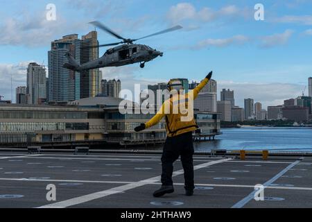 220211-N-FA490-3026 MANILA, Philippinen (Feb 11, 2022) – Boatswains Mate 2. Klasse Patrick Hix, aus Independence, Missouri, der dem Littoral Combat Ship USS Jackson (LCS 6) in Independence-Variante zugewiesen wurde, leitet einen MH-60s Hubschrauber, der den „Wildcards“ des Helicopter Sea Combat (HSC) Squadron 23 zugewiesen wurde, um auf dem Flugdeck von Jackson zu landen. Jackson und HSC-23, die an Destroyer Squadron (DESRON) 7 angeschlossen sind, befinden sich im Rotationseinsatz im Einsatzgebiet der US-7.-Flotte, um die Sicherheit und Stabilität in der Region zu unterstützen und mit alliierten und Partnermarines zusammenzuarbeiten, um maritime Seestreitkräfte bereitzustellen Stockfoto