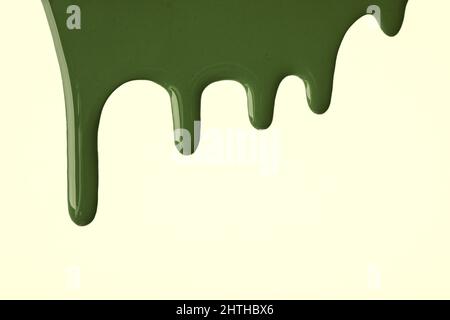 Dunkelgrüne flüssige Farbtropfen fließen auf hellem olivem Hintergrund herunter. Abstrakter Khaki-Hintergrund mit fließenden Tropfmustern. Acrylmalerei mit Polizist Stockfoto
