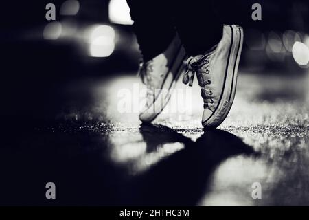 Sneaker Ballet. Zugeschnittenes Bild einer Person, die Turnschuhe trägt und auf den Zehen auf der Straße steht. Stockfoto