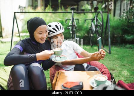 Schöne Radfahrer machen eine Pause im Café und machen Fotos zusammen Stockfoto