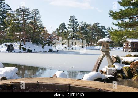 Ishikawa, Japan - 25. Februar 2022: Steinlaterne entlang des gefrorenen Kasumigaike-Teiches in Kenrokuen, einem der schönsten Gärten Japans, im Winter Mo Stockfoto