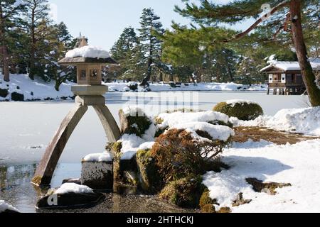 Ishikawa, Japan - 25. Februar 2022: Steinlaterne entlang des gefrorenen Kasumigaike-Teiches in Kenrokuen, einem der schönsten Gärten Japans, im Winter Mo Stockfoto