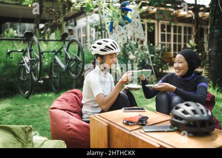 muslimischer Rennradfahrer sitzt in einem Café und hat eine Pause Stockfoto