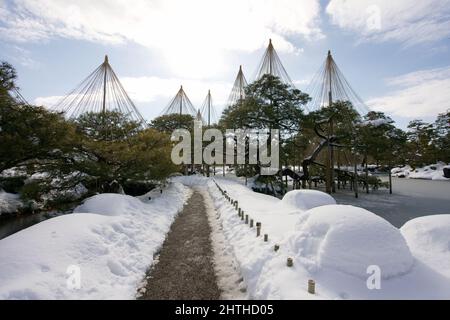 Ishikawa, Japan - 25. Februar 2022: Steinlaterne entlang des gefrorenen Kasumigaike-Teiches in Kenrokuen, einem der schönsten Gärten Japans, im Winter Mo Stockfoto