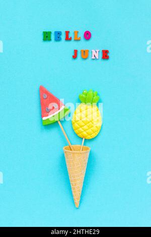 Hallo Juni bunten Text, Ananas und Wassermelone Lutscher in Eis Waffel Kegel auf blauem Papier Hintergrund. Konzept Urlaub oder Urlaub Kreativ Stockfoto