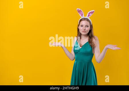 Geschossen glückliches Mädchen in flauschigen rosa Hasenohren, zeigt Finger zur Seite, zeigt etwas über einem leeren Raum isoliert auf einem gelben Studio-Hintergrund. Osterfeiertagskonzept Stockfoto