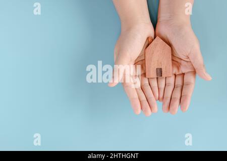 Future New Home Hope and Obdachlosenkonzept, Female Hands ist Holding House Model auf blauem Hintergrund. Wohngelegenheit und Immobilien Hypothekendarlehen. Stockfoto