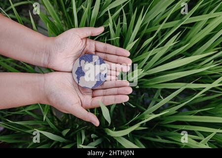 Save the Earth for Sustainable Lifestyles Konzept, Protect Planet Earth for Sustainable Resource. Menschliche Hände halten Globensymbol auf Grasblättern Bac Stockfoto