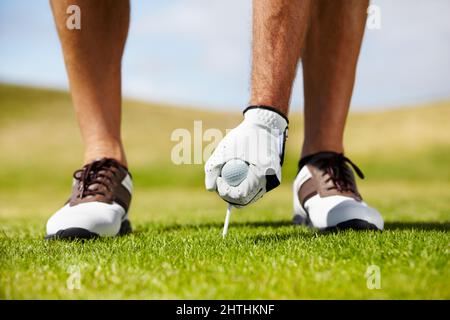 Der Anfang des Lochs. Ein Golfer, der sein T-Shirt auf dem Golfplatz in den Boden legt. Stockfoto