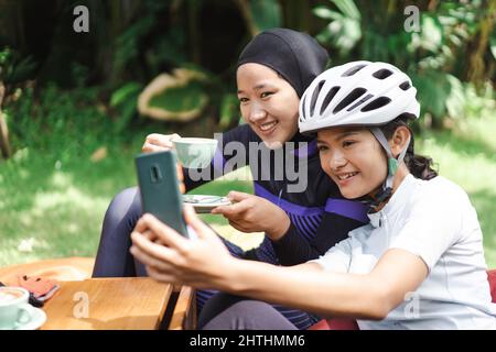 Schöne Radfahrer machen eine Pause im Café und machen Fotos zusammen Stockfoto