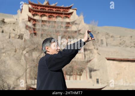 (220301) -- DUNHUANG, 1. März 2022 (Xinhua) -- das Foto vom 23. Februar 2022 zeigt Su Bomin in den Mogao-Grotten in Dunhuang, nordwestlich der Provinz Gansu in China. Su Bomin, Abgeordneter des Nationalen Volkskongresses (NPC), ebenfalls Dekan der Dunhuang Academy, arbeitet seit drei Jahrzehnten in den Mogao-Grotten, einem UNESCO-Weltkulturerbe in Dunhuang, nordwestlich der chinesischen Provinz Gansu. Su hat seit Beginn seines Dienstes als NPC-Stellvertreter eine Reihe von Vorschlägen zum Schutz kultureller Reliquien unterbreitet. Während der diesjährigen „zwei Sitzungen“, den jährlichen Sitzungen des Nationalen Volkskongs Stockfoto