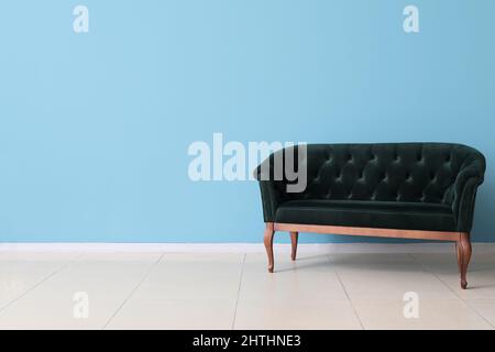Stilvolles grünes Sofa an der blauen Wand Stockfoto