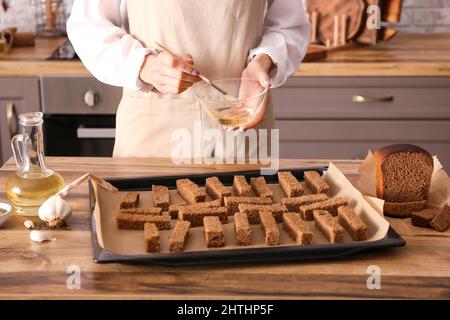 Frau bereitet Roggencroutons am Küchentisch zu, Nahaufnahme Stockfoto