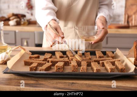 Frau bereitet Roggencroutons am Küchentisch zu, Nahaufnahme Stockfoto