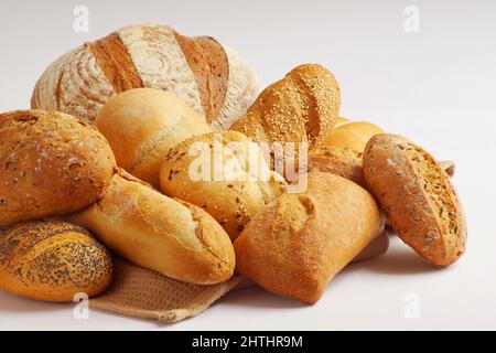 Verschiedene Arten von frisch gebackenen Backwaren mit einer knusprigen Kruste - Roggenbrot, Weizen, Brot, Baguette, Ciabatta, Brötchen - Legen Sie sich auf einen Tisch Stockfoto
