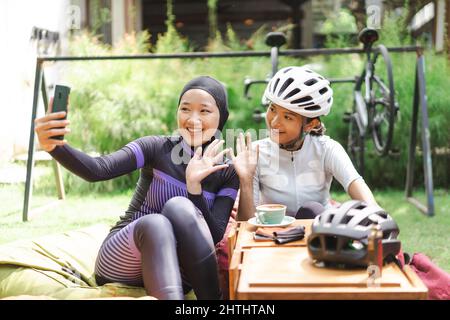 Schöne Radfahrer machen eine Pause im Café und machen Fotos zusammen Stockfoto