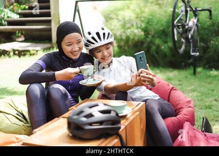 Schöne Radfahrer machen eine Pause im Café und machen Fotos zusammen Stockfoto