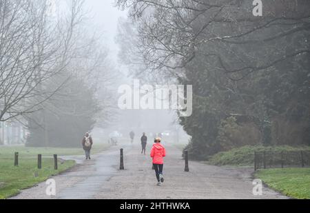 Brighton UK 1. March 2022 - Läufer und Wanderer im Preston Park Brighton an einem nebligen ersten Frühlingstag durch den meteorologischen Kalender, der am 1.. März beginnt : Credit Simon Dack / Alamy Live News Stockfoto