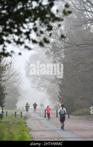 Brighton UK 1. March 2022 - Läufer und Wanderer im Preston Park Brighton an einem nebligen ersten Frühlingstag durch den meteorologischen Kalender, der am 1.. März beginnt : Credit Simon Dack / Alamy Live News Stockfoto