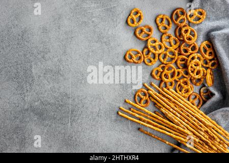 Kleine Brezeln und gesalzene Sticks. Knusprig gesalzener Snack auf einem Küchentisch. Draufsicht. Stockfoto