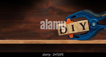 Nahaufnahme einer Feder-Kunststoffklemme und Text DIY (do it yourself), aus Holzblöcken, über einem Holzregal oder einer Werkbank mit Kopierfläche. Stockfoto