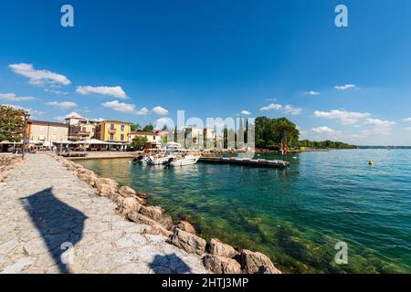 Kleiner Hafen des Dorfes Cisano mit Motorbooten, die festgemacht sind. Ferienort an der Küste des Gardasees. Bardolino Gemeinde, Verona, Italien. Stockfoto