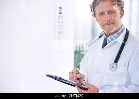 Die Hölle öffnet eure Augen für eine hellere Welt. Porträt eines reifen Optometrieers, der vor einem Augendiagramm steht. Stockfoto