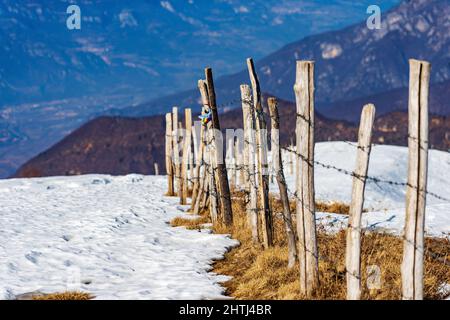 Zaun aus Stacheldraht und Holzpfosten für die Beweidung und Landwirtschaft in den Bergen, Regional Natural Park von Lessinia Plateau. Venetien, Italien, Europa. Stockfoto