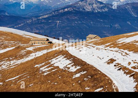 Milchviehbetriebe mit Kuhstall im Lessinia Plateau Regional Natural Park. Im Hintergrund die Bergkette des Monte Baldo im Winter, Venetien, Italien, Alpen. Stockfoto