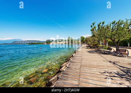 Promenade am Gardasee mit Holzboden und Bänken. Kleines Dorf Bardolino, Ferienort in der Provinz Verona, Venetien, Italien. Stockfoto