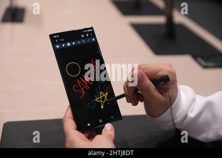 Barcelona, Spanien. 28.. Februar 2022. Ein Besucher schaut sich das Smartphone Samsung Galaxy S22 Ultra auf dem Stand von Samsung während des Mobile World Congress (MWC) an, der jährlichen Messe, die von GSMA auf der Fira de Barcelona, Spanien, organisiert wird. Stockfoto