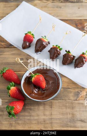 Erdbeeren mit Schokolade auf Holzgrund. Erdbeeren Tauchverfahren in Schokolade. Speicherplatz kopieren. Stockfoto
