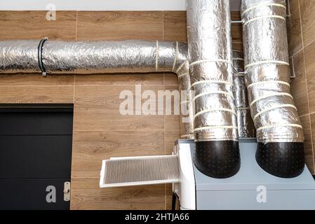 Mechanische Belüftung zu Hause mit Wärmerückgewinnung an der Wand, sichtbare schmutzige Filter, die aus dem Gerät herausragen. Stockfoto