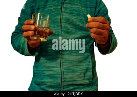 Mann im Vordergrund mit einem Glas Wasser und Medizin Stockfoto