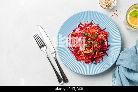 Gesunder veganer Frühlingssalat mit Kohl, Rüben und Karotten, gewürzt mit Dill und Sesam auf grauem Hintergrund. Das Konzept der alkalischen Ernährung. Stockfoto