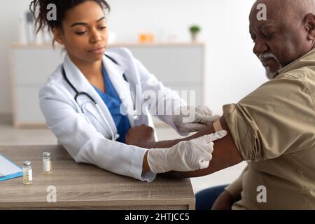 Schwarzer Reifer Mann, Der Geimpft Wird, Arzt, Der Selbstklebende Bandage Aufträgt Stockfoto
