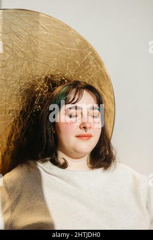Happy African American weibliche Modell trägt Seidenschal Top berühren Hals auf braunem Hintergrund im Studio und Blick auf die Kamera Stockfoto