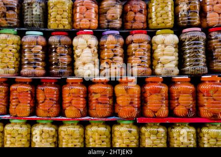 Die Fülle der Glasgefäße mit schmackhaftem eingelegtem Obst und Gemüse, die in Reihen auf dem Stand auf dem lokalen Markt Ägyptens angeordnet sind Stockfoto