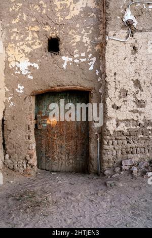 Veraltettes verlassene Haus mit verwitterter Steinmauer eine kleine schäbige Holztür auf der Straße der Altstadt in Ägypten Stockfoto