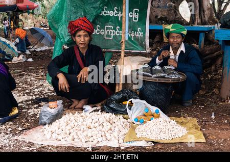 Kakku, Myanmar - 04.16.2017: Paar in traditioneller Kopfbedeckung, die auf dem Markt Garlics verkauft Stockfoto