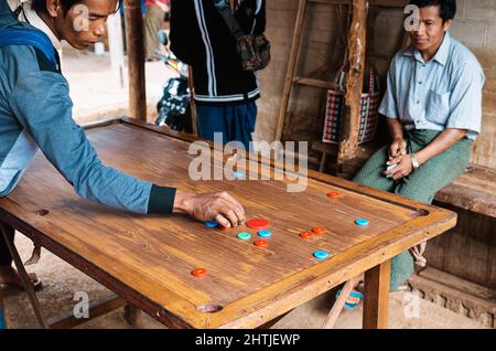 Bagan, Myanmar - 04.18.2017: Ethnische Männer spielen traditionelles südasiatisches Wildcarrom in einer armen Hütte in der antiken archäologischen Zone Stockfoto