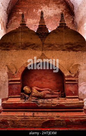 Alte Skulptur des schlafenden Buddha, die an einer schäbigen Steinmauer im Dhammayangyi Tempel in der Siedlung Bagan in Myanmar aufgestellt wurde Stockfoto