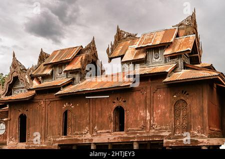 Fassade des alten Shwe Yan Pyay Klosters mit einer schäbigen Mauer, die sich gegen den bewölkten Himmel auf der Straße der Gemeinde Nyaungshwe in Myanmar befindet Stockfoto