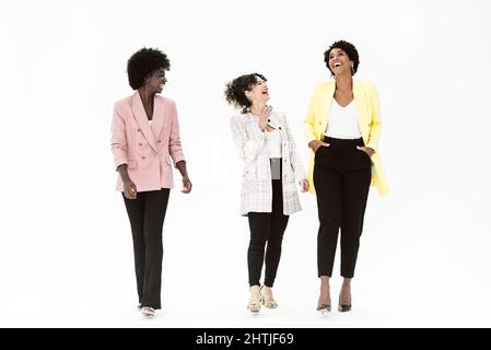 Gruppe von fröhlichen multiethnischen Frauen in stilvoller Kleidung stehen zusammen isoliert auf weißem Hintergrund im Studio Stockfoto
