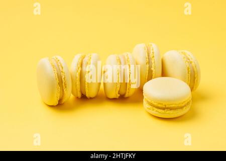 Ein Haufen von süßen, zitronenaromatisierten Macarons mit leckerer Füllung, serviert auf gelbem Hintergrund in einem hellen Raum Stockfoto