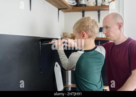 Vater und Sohn machen gemeinsam Hausrenovierungen. Mit Schraubendreher. Vater lehrt Kind Werkzeuge zu verwenden Stockfoto